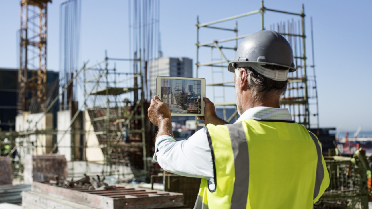 Rear view of male architect photographing construction site through digital tablet